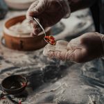 Chef preparing Nepali momos by filling dough with fresh vegetables.